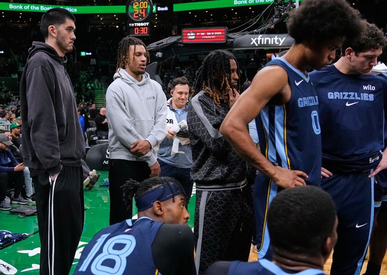 Ja Morant, base de los Grizzlies de Memphis, segundo desde la izquierda, quien está marginado por una lesión, observa al equipo reunirse durante el final del primer cuarto de un juego de baloncesto de la NBA contra los Celtics de Boston, el miércoles 12 de noviembre de 2025, en Boston. (AP Photo/Charles Krupa)