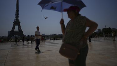 ARCHIVO - Varias personas caminan por la plaza de Trocadero, cerca de la torre Eiffel, en plena ola de calor, el 2 de julio de 2025, en París. (AP Foto/Christophe Ena, archivo)
