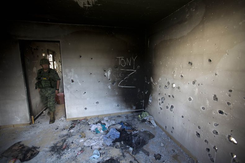 ARCHIVO - Un soldado ingresa a una casa acribillada a balazos cubierta por las iniciales del Cartel del Golfo (CDG) y Los Zetas (Z) en Ciudad Victoria, estado de Tamaulipas, México, el 6 de septiembre de 2014. (AP Foto/Eduardo Verdugo, Archivo)