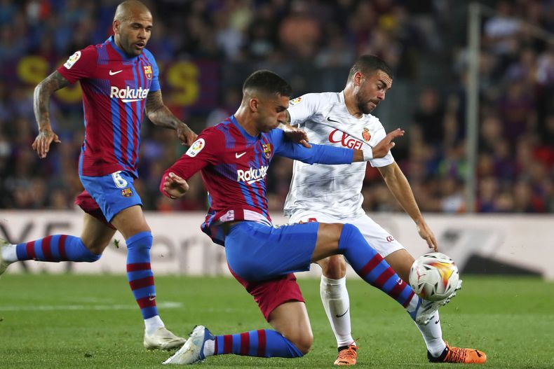 ARCHIVO - El español Ferran Torres, en el centro, del Barcelona, disputa el balón con el español Dani Rodríguez, del Mallorca, durante un partido de fútbol de LaLiga española entre el FC Barcelona y el Mallorca en el estadio Camp Nou en Barcelona, España, el 1 de mayo de 2022. (AP Photo/Joan Monfort, archivo)
