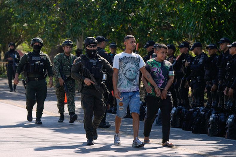 La policía escolta a dos presuntos miembros de grupos paramilitares, esposados entre sí, tras su detención en Santa Marta, Colombia, el miércoles 23 de septiembre de 2026. (AP Foto/Fernando Vergara)