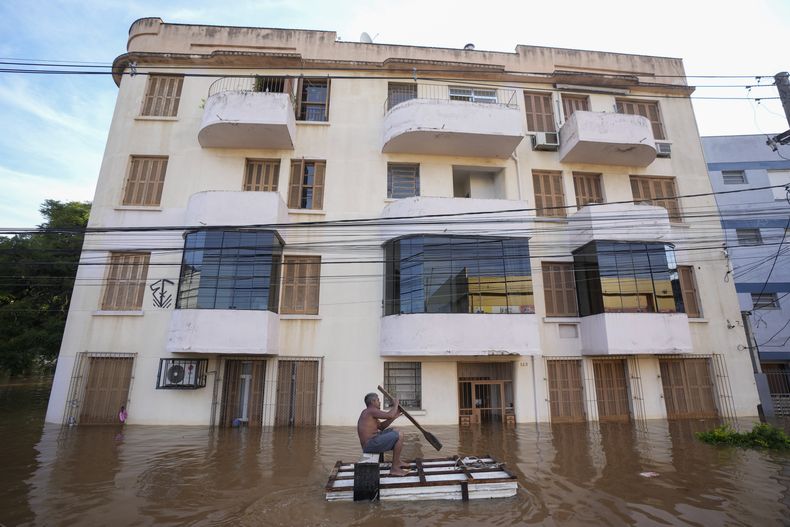 Un hombre rema en un bote improvisado a través de una calle inundada por las fuertes lluvias, en Porto Alegre, Brasil, martes 7 de mayo de 2024. (AP Foto/Andre Penner)