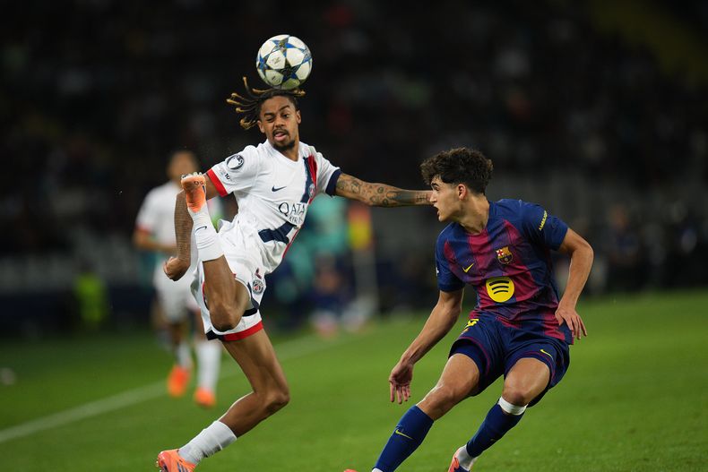 Bradley Barcola, izquierda, del PSG, encara a Pau Cubarsi, del Barcelona, con una jugada de fantasía durante el partido de fútbol de la Liga de Campeones entre Barcelona y Paris Saint-Germain en el estadio Olímpico Lluis Companys, en Barcelona, España, el miércoles 1 de octubre de 2025. (AP Foto/Emilio Morenatti)