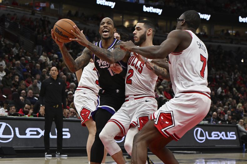 DeMar DeRozan, tercero desde la derecha, de los Kings de Sacramento, busca encestar con un tiro ante la presión defensiva de Lonzo Ball (2), Jalen Smith (7) y Josh Giddy, de los Bulls de Chicago, durante a primera mitad del juego de baloncesto de la NBA, el domingo 12 de enero de 2025, en Chicago. (AP Foto/Paul Beaty)