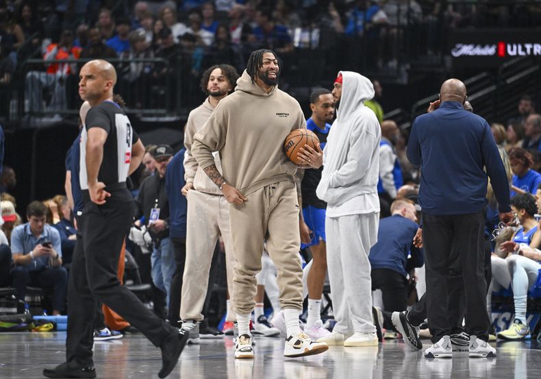Anthony Davis, centro, de los Mavaricks de Dallas, con ropa de calle debido a una lesión, convive en la duela con sus compañeros durante la primera mitad del juego de baloncesto de la NBA contra los Pistons de Detroit, el viernes 21 de marzo de 2025, en Dallas, Teas. (AP Foto/Albert Pena)