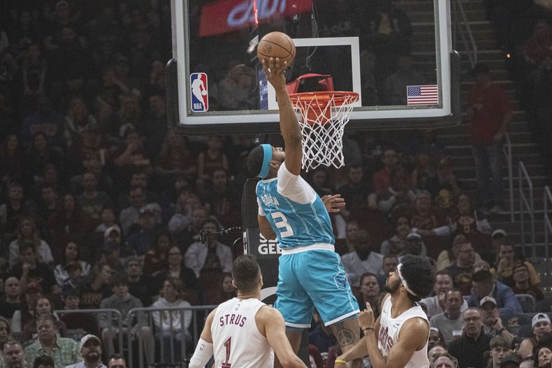 Marques Bolden de los Hornets de Charlotte salta para clavar el balón sobre Max Strus y Jarrett Allen de los Cavaliers de Cleveland en el encuentro de la NBA del domingo 14 de abril del 2024. (AP Foto/Phil Long)
