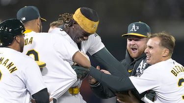 Lawrence Butler (centro), de los Atléticos de Oakland, festeja con sus compañeros tras conectar el hit del triunfo sobre los Nacionales de Washington, en la décima entrada del juego del viernes 12 de abril de 2024 (AP foto/Tony Avelar)