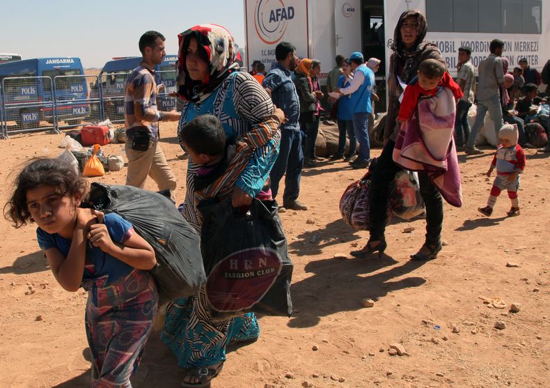 En esta foto del 23 de septiembre de 2014, miles de refugiados sirios entran a Turqu&iacute;a en por el cruce Yumurtalik cerca de la localidad turca de Suruc. Los refugiados dicen que su poblaci&oacute;n se ha convertido en un pueblo fantasma, solo quedan