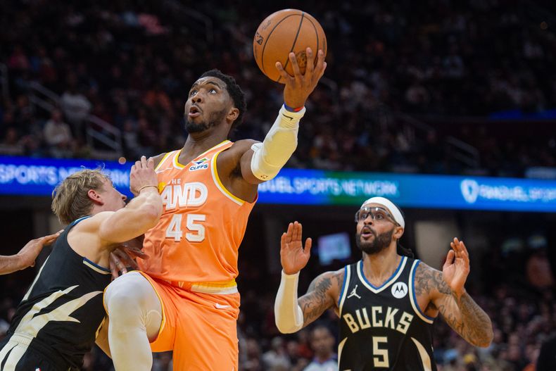 Donovan Mitchell (45), de los Cavaliers de Cleveland, alista un enceste sobre AJ Green, izquierda, y frente a Gary Trent Jr. (5), de los Bucks de Milwaukee, durante la segunda mitad del juego de baloncesto de la NBA, el lunes 17 de noviembre de 2025, en Cleveland. (AP Foto/Phil Long)