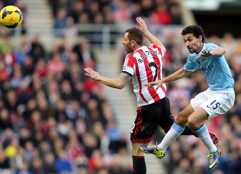 El jugador de Manchester City Jes&uacute;s Navas, der., disputa la pelota con su rival de Sunderland Phil Bardsley en un encuentro de la Liga Inglesa en Sunderland el 11 de noviembre del 2013 (AP Foto/Scott Heppell)