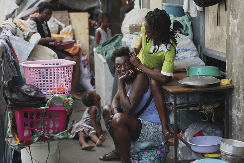 Una mujer peina el cabello de otra en un refugio para familias desplazadas por la violencia de pandillas, en Puerto Príncipe, Haití, el jueves 22 de mayo de 2025. (AP Foto/Odelyn Joseph)