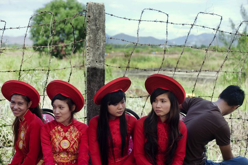 Personas al lado de un campo contaminado antes del inicio de una ceremonia para inaugurar un programa de descontaminado de zonas contaminadas durante la Guerra de Vietnam, en lo que fue la base militar estadounidense de Danang, Vietnam, el 9 de agosto del 2012. (AP foto/Maika Elan)