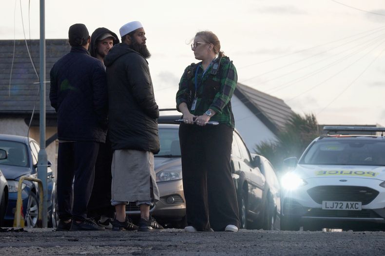 Lugareños observan los daños a la entrada de la mezquita en Peacehaven, luego de un ataque incendiario, en East Sussex, Inglaterra, el domingo 5 de octubre de 2025. (Jamie Lashmar/PA vía AP)