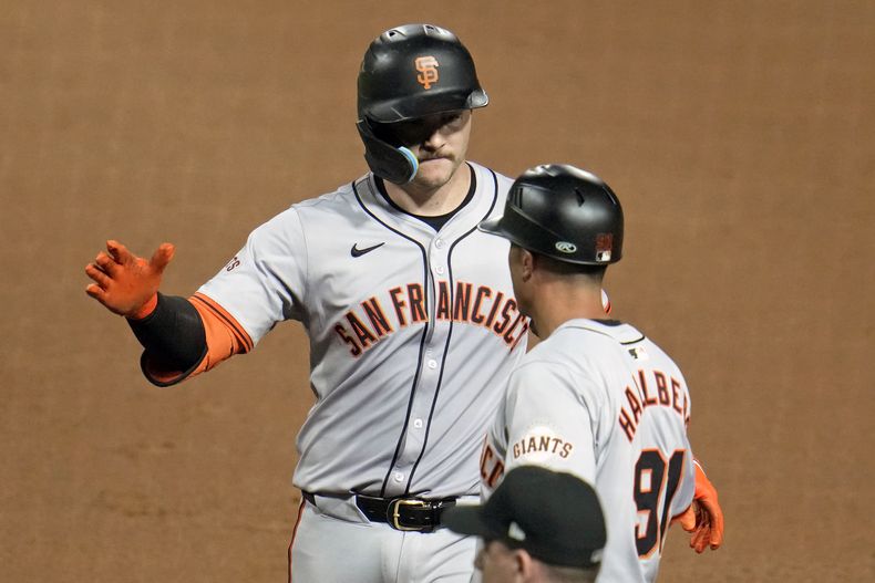 Patrick Bailey, de los Gigantes de San Francisco, festeja con el coach de la inicial Mark Hallberg luego de empujar la carrera de la ventaja ante los Piratas de Pittsburgh, el miércoles 22 de mayo de 2024 (AP Foto/Gene J. Puskar)