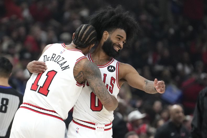 DeMar DeRozan, de los Bulls de Chicago, abraza a Coby White, quien encestó en el partido ante los Grizzlies de Memphis, el sábado 20 de enero de 2024 (AP Foto/Charles Rex Arbogast)