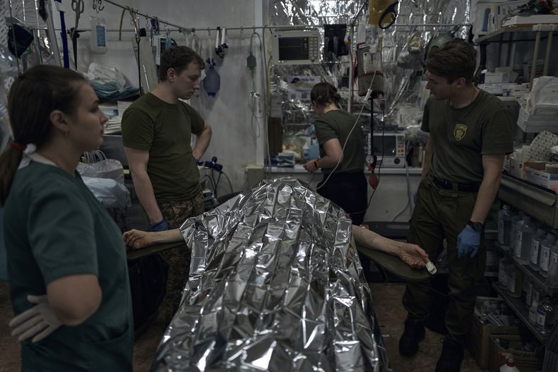 Un soldado ucraniano herido recibe primeros auxilios en un punto de estabilización médica cerca de Bájmut, en la región de Donetsk, Ucrania, el 19 de junio de 2023. (AP Foto/Libkos)