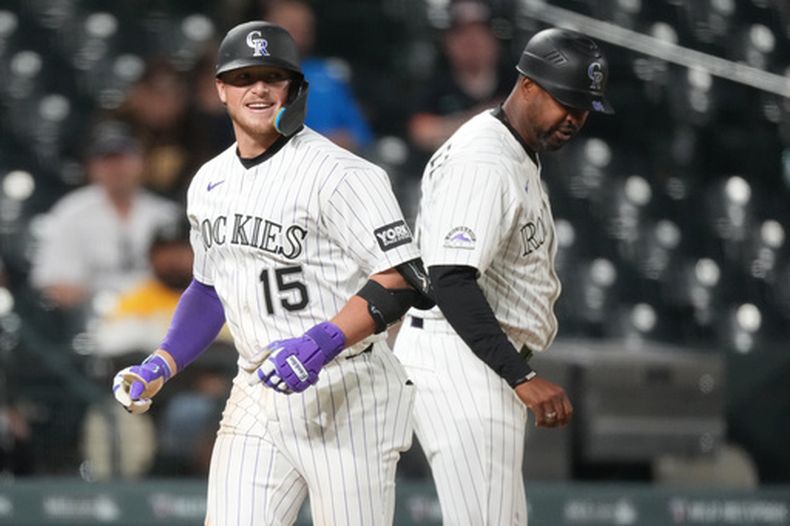 Hunter Goodman (15), de los Rockies de Colorado, pasa frente al coach de tercera base Andy González mientras recorre las bases después de batear un jonrón solitario frente a Wandy Peralta, de los Padres de San Diego, en la octava entrada del juego de béisbol de Grandes Ligas del miércoles 22 de abril de 2026, en Denver. (AP Foto/David Zalubowski)