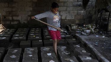 Yosbelin Pérez, quien regresó a Venezuela desde México con su esposo y sus cinco hijos después de abandonar los planes de llegar a Estados Unidos en medio de la represión migratoria del presidente Donald Trump, cubre moldes con aluminio fundido para hacer planchas para cocinar, en Maracaibo, Venezuela, el lunes 16 de junio de 2025. (AP Foto/Matias Delacroix)