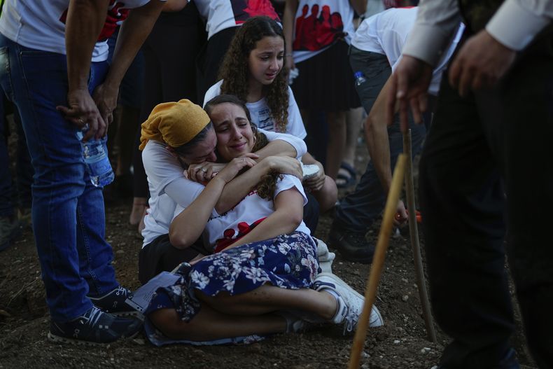 Varias personas lloran junto a las tumbas de las ciudadanas británicas-israelíes Lianne Sharabi y sus dos hijas, Noiya, de 16 años, y Yahel, de 13, durante su funeral en Kfar Harif, Israel, el 25 de octubre de 2023. Las tres fueron asesinadas por insurgentes de Hamás el 7 de octubre en el kibutz de Beeri, cerca de la frontera con la Franja de Gaza. Más de 1.400 personas fallecieron y unas 240 fueron capturadas en un ataque transfronterizo sin precedentes lanzado por insurgentes de Hamás desde la Franja de Gaza. (AP Foto/Ariel Schalit)