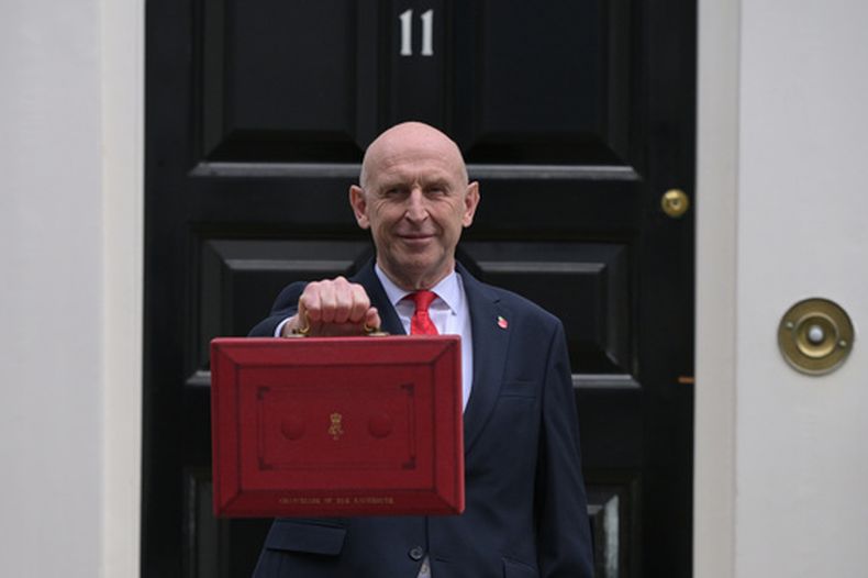 El ministro de Economía de Reino Unido, John Healey, posa en la entrada de 11 Downing Street con la caja roja ministerial antes de dirigirse a la Cámara de los Comunes para presentar la declaración del presupuesto en Londres, el miércoles 28 de octubre de 2026. (AP Foto/Thomas Krych)