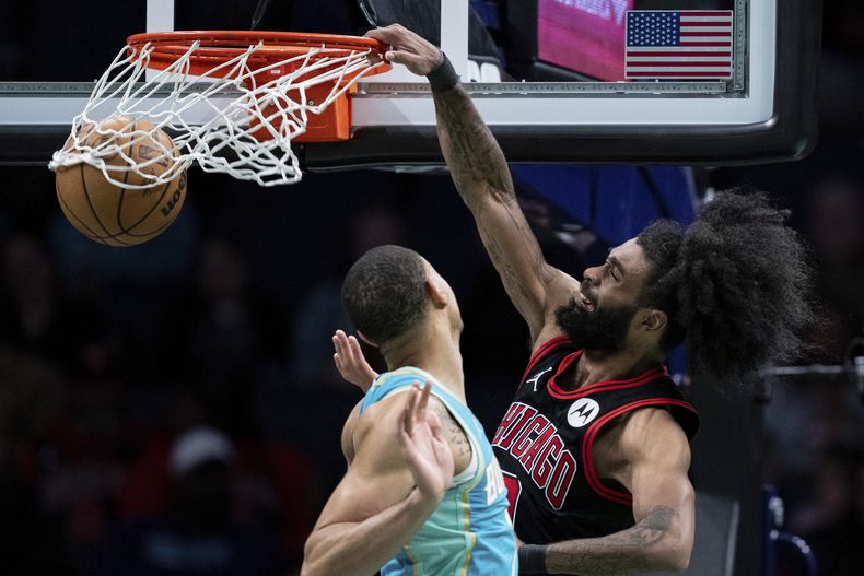 Coby White, de los Bulls de Chicago, realiza una clavada frente a Bryce McGowens, de los Hornets de Charlotte, en el partido del miércoles 31 de enero de 2024 (AP Foto/Jacob Kupferman)
