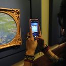 Un visitante toma fotografías de una pintura de Claude Monet durante una gira de prensa de la exposición: La Revolución Impresionista, en el Palacio de Bellas Artes en la Ciudad de México, el lunes 24 de marzo de 2025. (Foto AP/Fernando Llano)