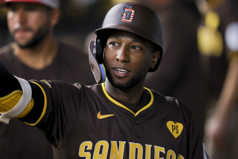 Jurickson Profar, de los Padres de San Diego celebra junto a sus compañeros de equipo en el dugout luego de completar exitosamente un toque de sacrificio durante el octavo episodio del juego de béisbol ante los Rangers de Texas, el jueves 4 de julio de 2024, en Arlington, Texas. (AP Foto/Gareth Patterson)