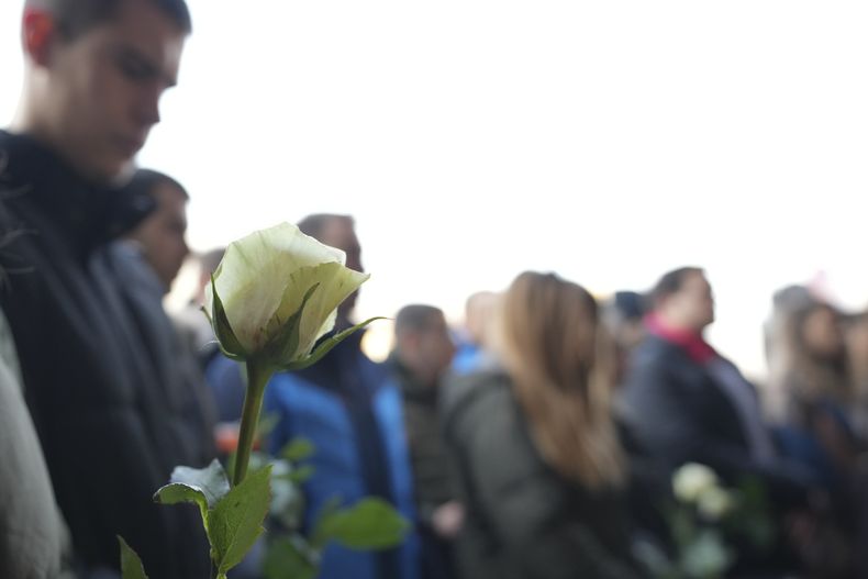 Estudiantes sostienen flores blancas frente al edificio del tribunal durante un veredicto en el juicio de los padres de un niño que mató a 9 estudiantes y a un guardia de seguridad en un tiroteo escolar en 2023, en Belgrado, Serbia, el lunes 30 de diciembre de 2024. (AP Foto/Darko Vojinovic)