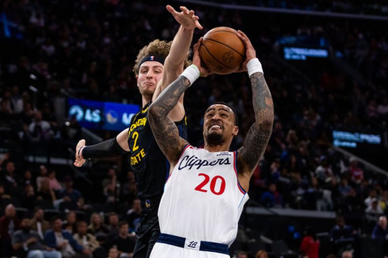John Collins (20), de los Clippers de Los Ángeles, busca encestar por delante de Brandin Podziemski (2), de los Warriors de Golden State, durante la primera mitad del juego de baloncesto de la NBA, el domingo 12 de abril de 2026, en Inglewood, California. (AP Foto/Ethan Swope)