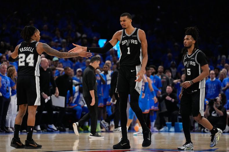 El alero de los Spurs de San Antonio Victor Wembanyama celebra con sus compañeros Devin Vassell (24) y Stephon Castle en el juego 1 de las Finales de la Conferencia Oeste ante el Thunder de Oklahoma City el lunes 18 de mayo del 2026. (AP Foto/Tony Gutierrez)