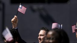 Un hombre, que forma parte de un grupo de 50 nuevos ciudadanos estadounidenses oriundos de 25 países diferentes, ondea una bandera de Estados Unidos durante una ceremonia de naturalización antes del partido de los Padres de San Diego ante los Mellizos de Minnesota, en Petco Park, el miércoles 21 de agosto de 2024, en San Diego. (AP Foto/Gregory Bull)