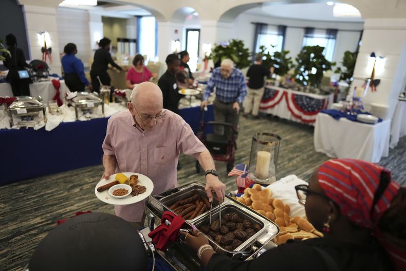 Un anciano se sirve del buffet por el Día de la Independencia de Estados Unidos, en la residencia para ancianos Toby and Leon Cooperman Sinai Residences, el 4 de julio de 2025, en Boca Raton, Florida. (AP Foto/Rebecca Blackwell)