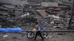 En esta imagen de archivo, un niño palestino camina con una bicicleta de la mano entre los escombros de un edificio alcanzado por un ataque aéreo israelí, en la Ciudad de Gaza, el 8 de octubre de 2023. (AP Foto/Fatima Shbair, archivo)