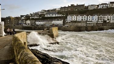 americateve | La gente camina mientras las olas se estrellan conra el malec&oacute;n que protege la bah&iacute;a de Porthleven, Cornwall, en el domingo 27 de octubre de 2013. (Foto AP/PA, Ben Birchall)