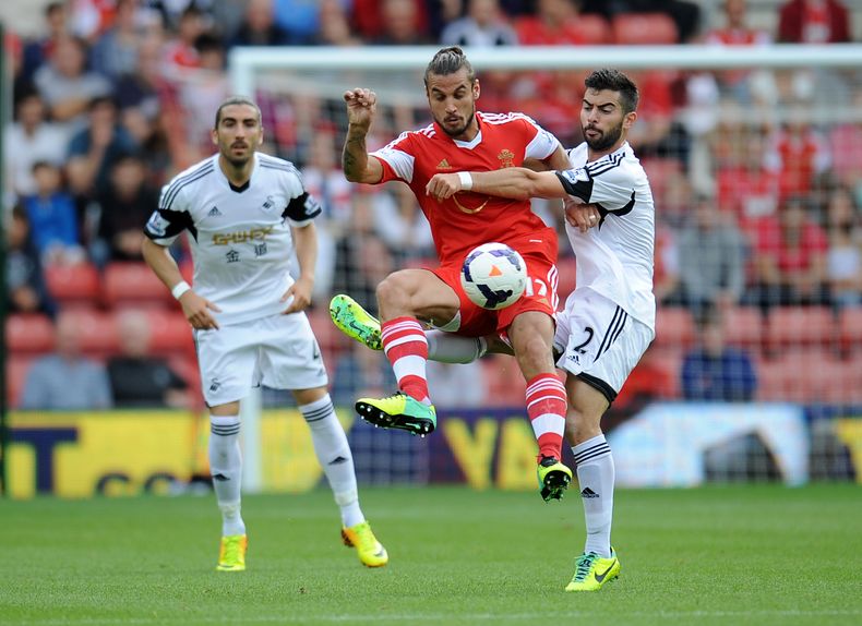 El argentino Pablo Daniel Osvaldo, de Southampton, es embestido por Jordi Amat, de Swansea, en un encuentro de la Liga Inglesa el 6 de octubre del 2013 en Southampton (AP Foto/ Clive Gee/PA ) UNITED KINGDOM OUT - NO SALES - NO ARCHIVES