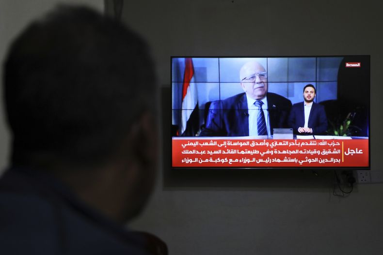Un hombre mira las noticias en la televisión, que muestran imágenes de Ahmed al-Rahawi, el primer ministro del gobierno controlado por los hutíes, quien murió en los ataques israelíes del jueves contra la capital Saná, Yemen, el sábado 30 de agosto de 2025. (AP Foto/Osamah Abdulrahman)