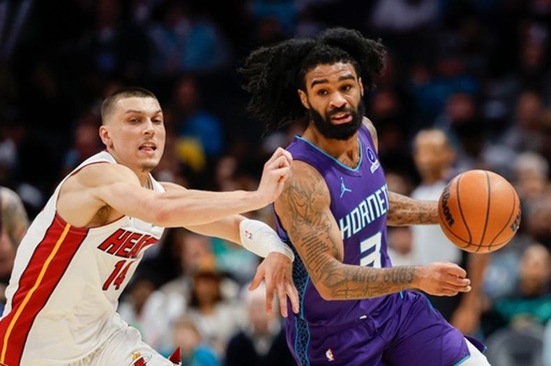 El base de los Hornets de Charlotte Coby White avanza con el balón frente a Tyler Herro del Heat de Miami el martes 17 de marzo del 2026. (AP Foto/Nell Redmond)