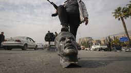 Un rebelde sirio sobre un busto de fallecido presidente sirio Hafez Assad en Damasco el 8 de diciembre del 2024. (AP foto/Hussein Malla)