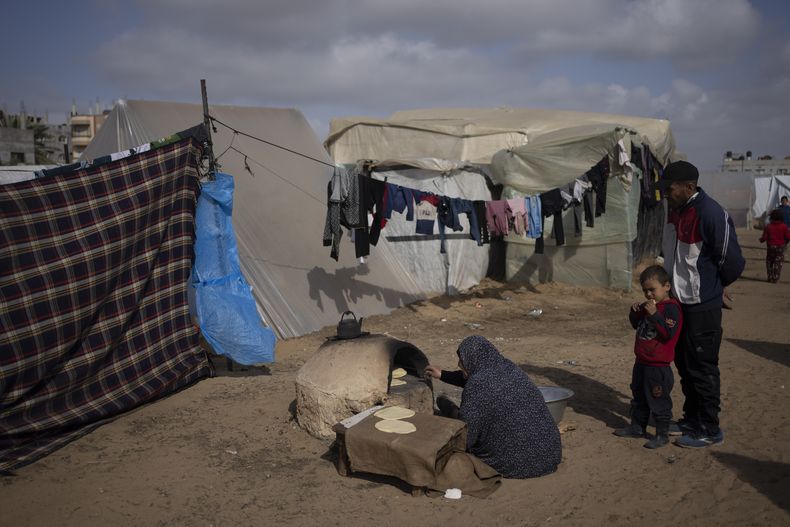 Palestinos desplazados por la ofensiva terrestre israelí en la Franja de Gaza cocinan en un campamento improvisado en Rafah, el martes 23 de enero de 2024. (AP Foto/Fatima Shbair)