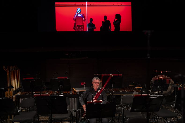 Un músico ensaya mientras los técnicos trabajan sobre el escenario antes de una representación de Turandot, la ópera de Giacomo Puccini, en el Teatro Real de Madrid, el 14 de julio de 2023. Desde hace ocho años, el Teatro Real ofrece la retransmisión gratuita de las óperas que se representan en su escenario a pueblos y ciudades de toda España. El objetivo es incentivar el interés por la ópera y librarla de su etiqueta de elitista. (AP Foto/Bernat Armangué)