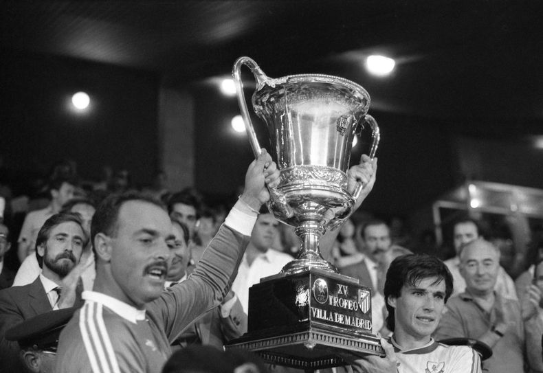 ARCHIVO - Foto del 23 de agosto de 1987,el capitán del Liverpool Alan Hansen sostiene el trofeo de la Villa de Madrid junto al portero Bruce Grobbelaar tras la victoria ante el Atlético de Madrid. El domingo 9 de junio del 2024, Hansen está hospitalizado de gravedad, según informó el equipo. (AP Foto/Toka, Archivo)