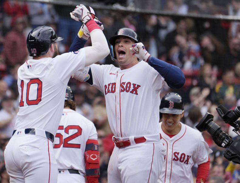 Triston Casas (centro), de los Medias Rojas de Boston celebra tras impactar un jonrón de tres carreras que también remolcó a Trevor Story (10), y Masataka Yoshida (derecho al fondo), en el primer juego de la doble tanda ante los Mellizos de Minnestoa, el domingo 22 de septiembre de 2024, en Boston. (AP Foto/Michael Dwyer)