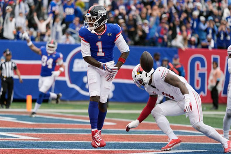 El receptor abierto de los Giants de Nueva York, Malik Nabers (1), celebra la recepción de un touchdown frente al apoyador de los Cardinals de Arizona, Mack Wilson Sr. (derecha), durante un partido de fútbol americano de la NFL en East Rutherford, Nueva Jersey, el 4 de octubre de 2026. (Foto AP/Seth Wenig)