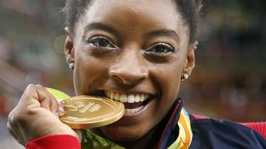 La gimnasta estadounidense Simone Biles muerde su medalla de oro tras ganar la medalla de oro en el concurso completo de los Juegos Olímpicos de Río de Janeiro 2016, el 11 de agosto de 2016. (AP Foto/Dmitri Lovetsky)