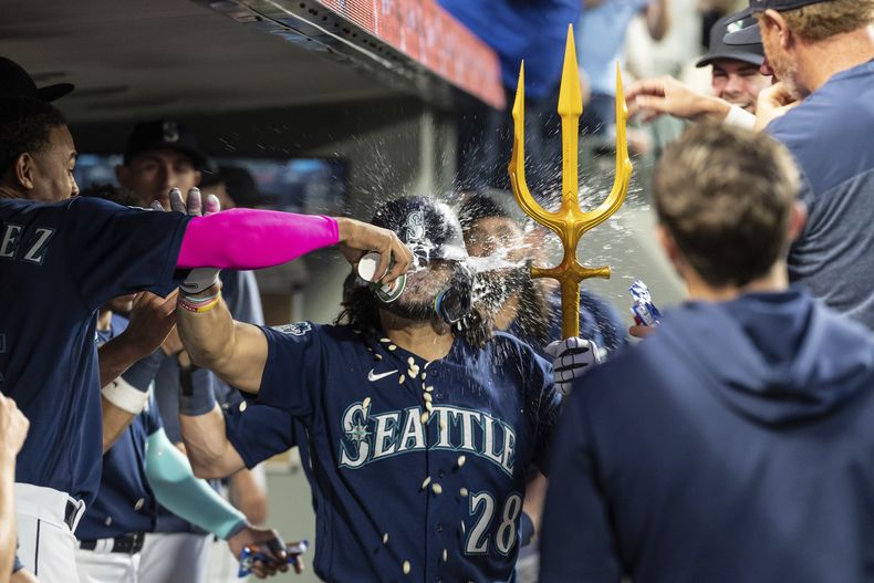El dominicano de los Marineros de Seattle Julio Rodriguez le lanza agua al venezolano Eugenio Suárez tras conectar un jonrón de dos carreras frente al relevista de Oliver Ortega de los Mellizos de Minnesota en el encuentro del lunes 17 de julio del 2023. (AP Foto/Stephen Brashear)