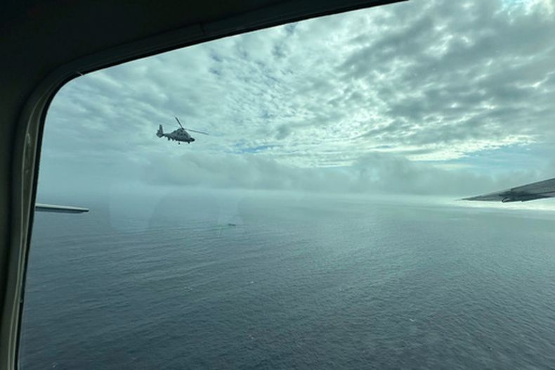 Un helicóptero militar chino vuela cerca de una aeronave filipina en el banco de arena Scarborough el 18 de febrero del 2025. (AP foto/Joeal Calupitan)