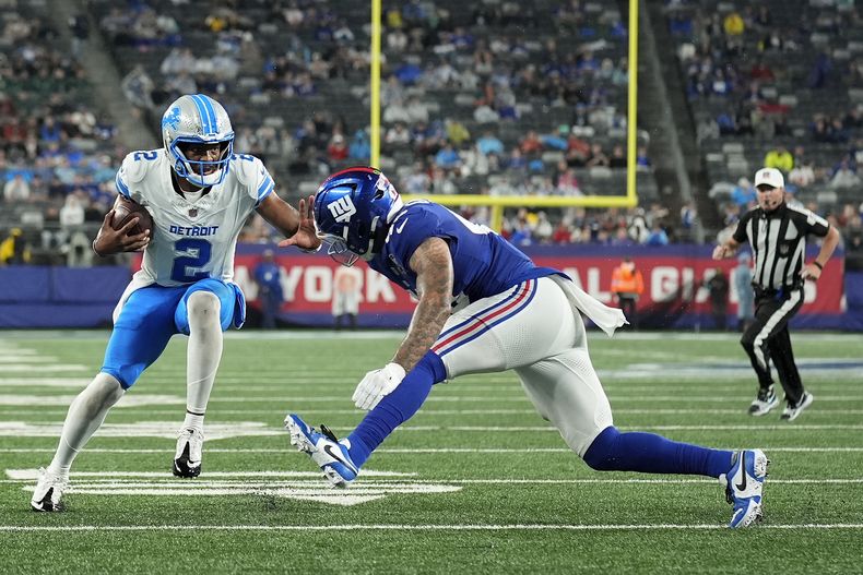 Hendon Hooker (2), quarterback de los Lions de Detroit, acarrea el balón en contra de Darrian Beavers (43), linebacker de los Giants de Nueva York, durante el tercer cuarto del juego de pretemporada de la NFL, el jueves 8 de agosto de 2024, en East Rutherford, Nueva Jersey. (AP Foto/Seth Wenig)
