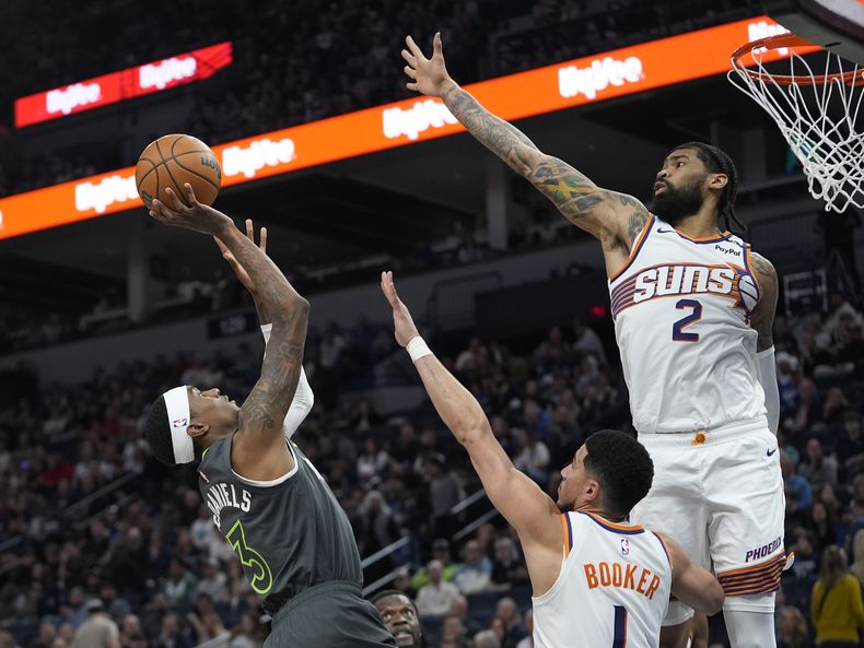 Jaden McDaniels, de los Timberwolves de Minnesota, dispara frente a Devin Booker y Nick Richards, de los Suns de Phoenix, el viernes 28 de marzo de 2025 (AP Foto/Abbie Parr)