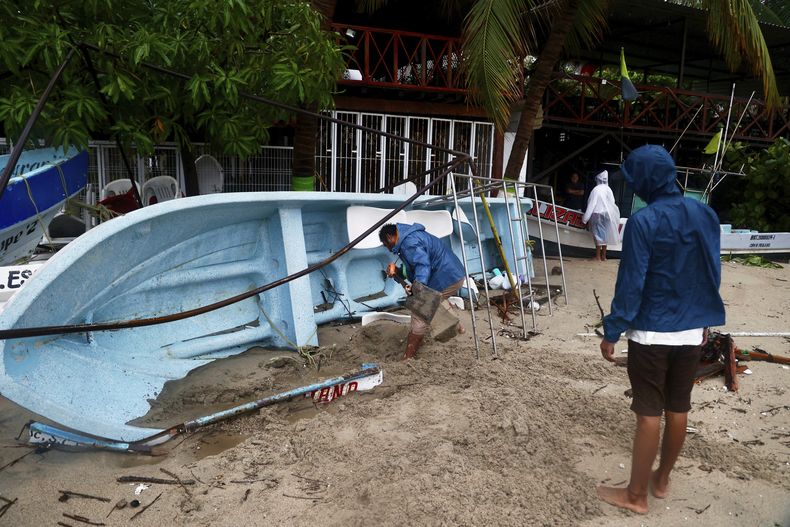 Una persona quita arena de una lancha que fue llevada a la orilla como medida de precaución luego de que el huracán Erick azotó Puerto Escondido, el jueves 9 de junio de 2025, en el estado de Oaxaca, México. (AP Foto/Luis Alberto Cruz)
