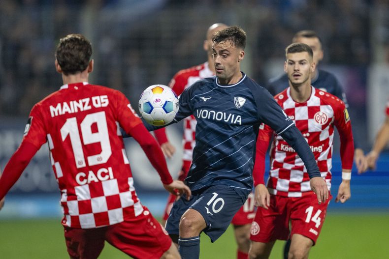 Philipp Forster del Bochum es marcado por Anthony Caci, izquierda, y Tom Krauss, jugadores del Mainz durante el partido de la Liga Alemana en el Vonovia Ruhrstadion, en Bochum, Alemania, el viernes 27 de octubre de 2023. (David Inderlied/dpa via AP)